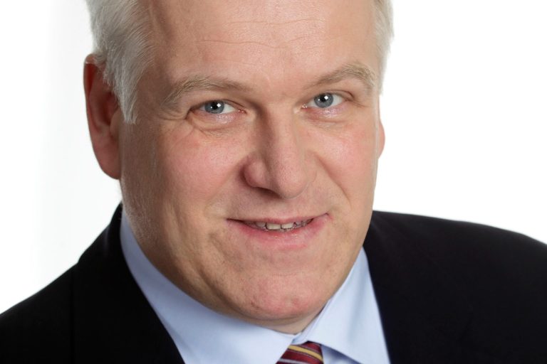 Dipl.-Ing. (FH) Volker Huth Portrait eines lächelnden Mannes mit kurzem, grauem Haar in formeller Kleidung.